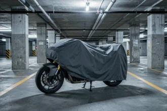 Moto couverte d'une housse de protection garée seule dans un parking souterrain en béton, illustrant le stationnement longue durée sans usage