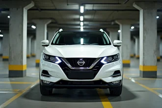 Nissan Qashqai blanc garé dans un parking urbain, vue 3/4 avant mettant en valeur le capot moteur et la calandre