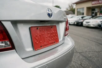 Plaque d'immatriculation rouge temporaire fixée sur le pare-chocs arrière d'une voiture d'occasion dans un lot de concessionnaire