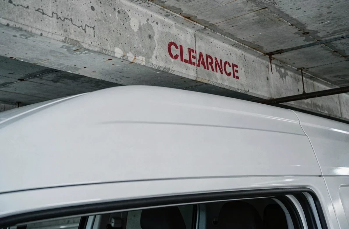Détail du toit d'un utilitaire L2H2 frôlant un plafond en béton dans un parking souterrain avec avertissement de hauteur